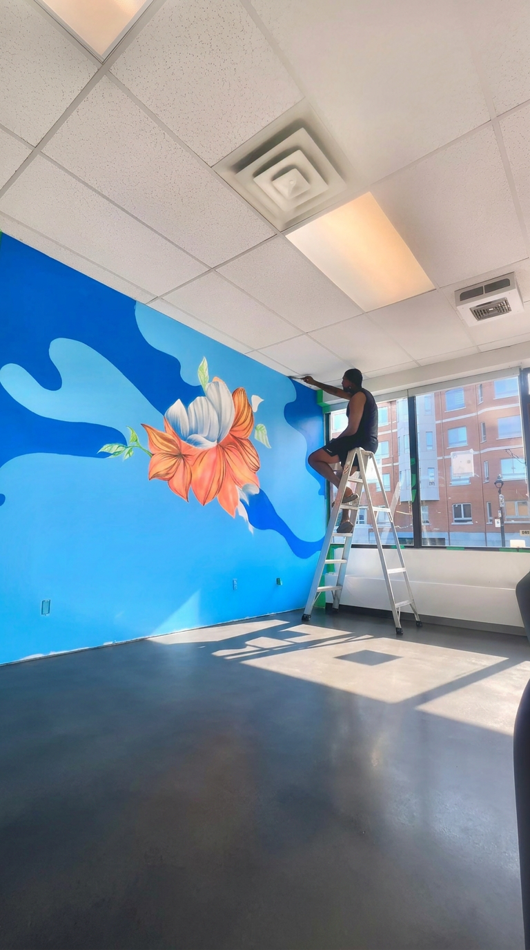 Dino painting a floral mural in an interior space