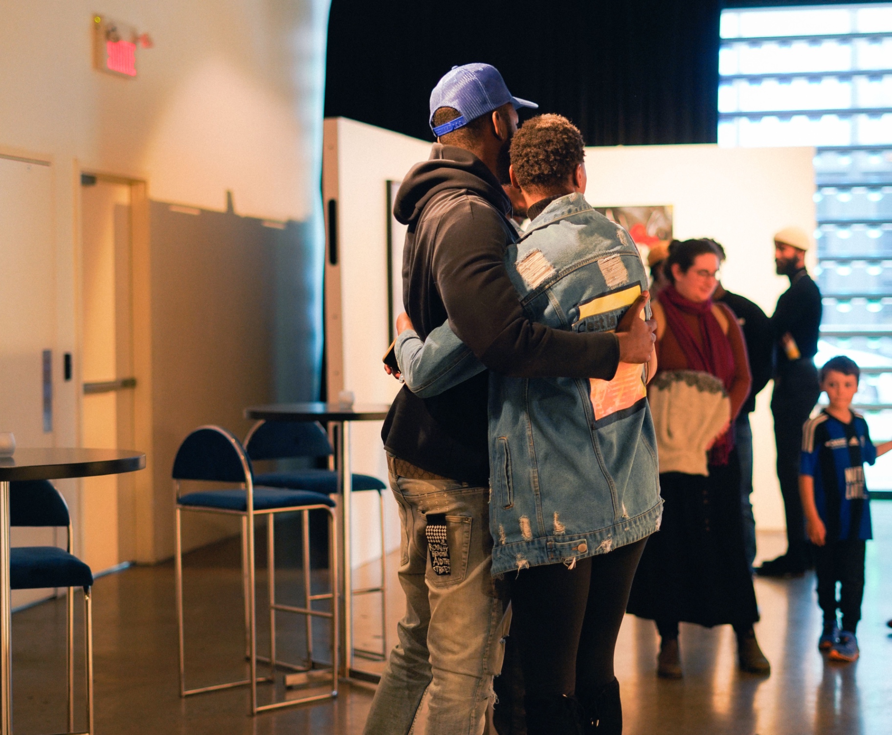 Two people embracing inside an art gallery during a vernissage